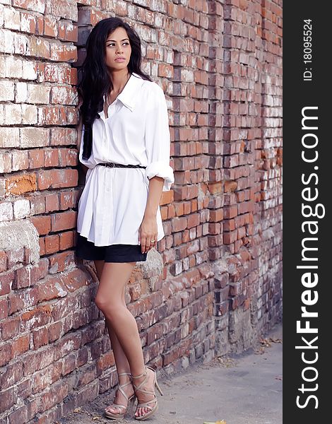 Cute brunette posing against a brick wall. Cute brunette posing against a brick wall