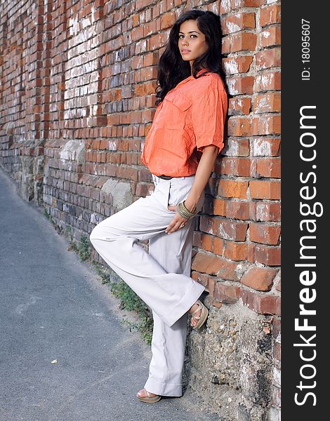 Cute brunette posing against a brick wall. Cute brunette posing against a brick wall