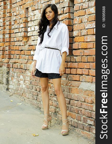 Cute brunette posing against a brick wall. Cute brunette posing against a brick wall