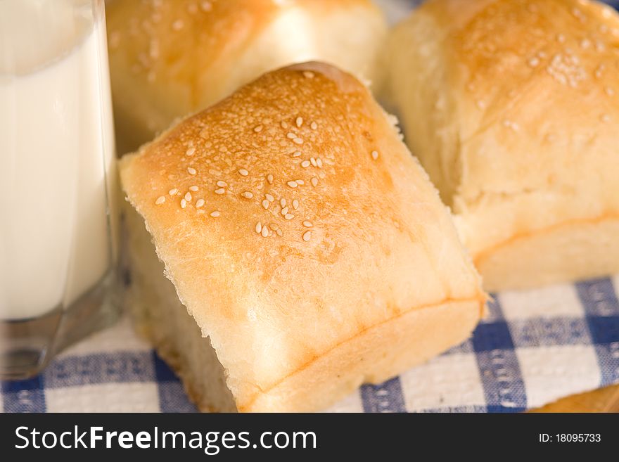 Homemade bread buns with sesame seeds and glass of milk