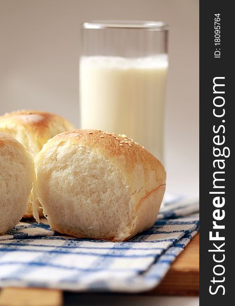 Homemade bread buns with sesame seeds and glass of milk