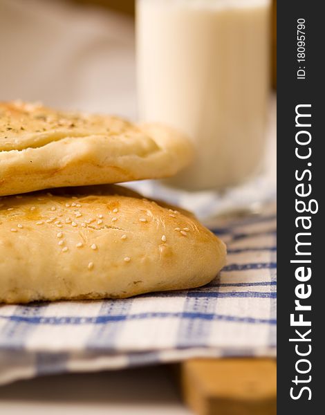 Homemade bread buns with sesame seeds and glass of milk