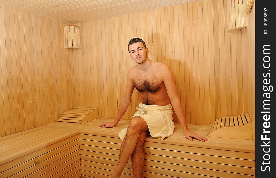 Young handsome man in a towel relaxing in a russian wooden sauna. Young handsome man in a towel relaxing in a russian wooden sauna