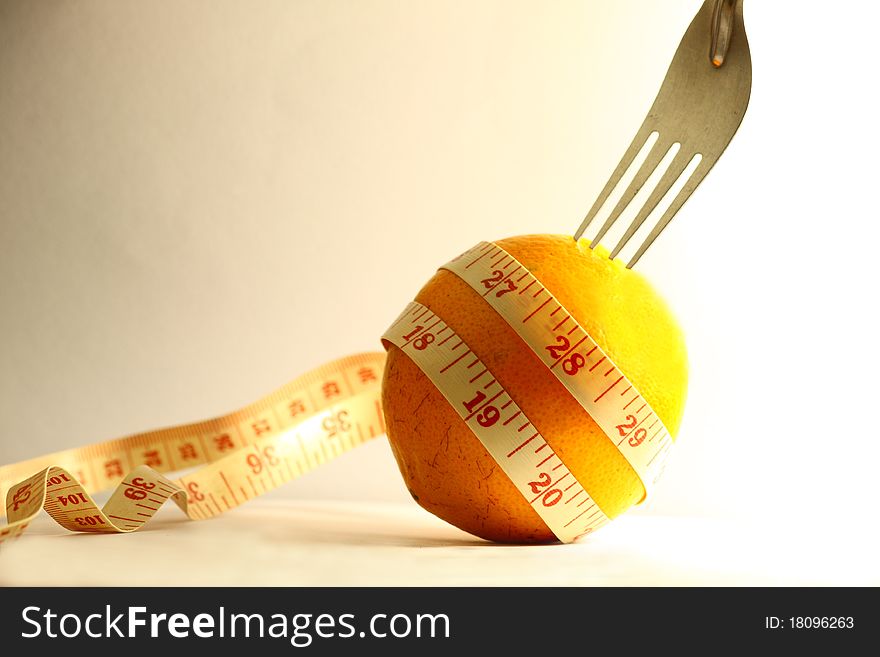 Orange with measurement tape and fork on white background