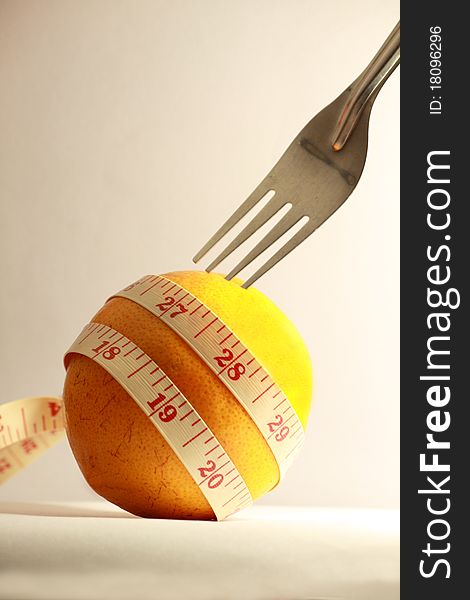 Orange with measurement tape and fork on white background