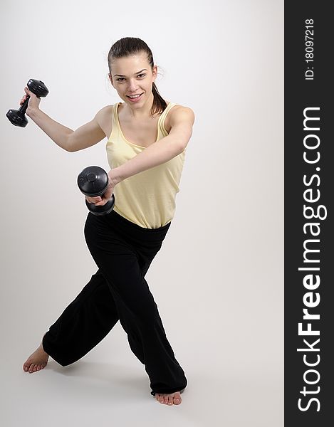 Young woman training her body and muscles with dumbbells. Young woman training her body and muscles with dumbbells