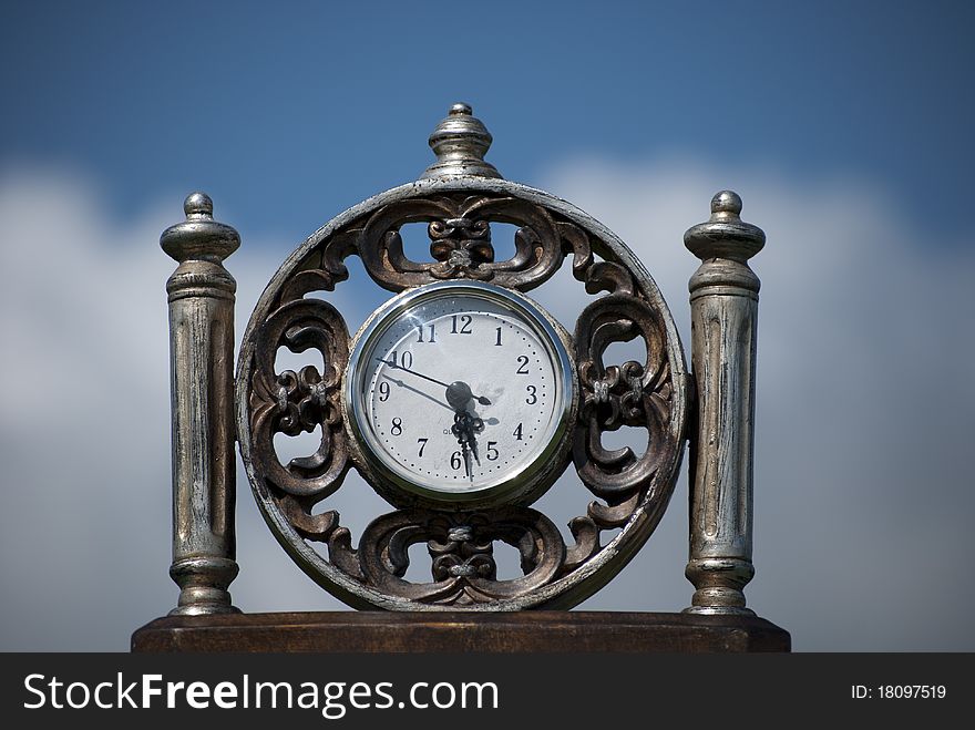A clock with clouds and the sky as a background