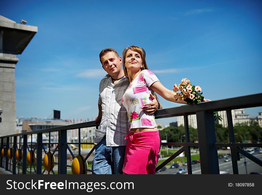 Young happy man and woman at romantic walk on bridge in big city