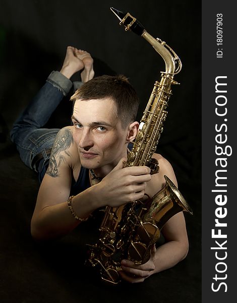 The young jazzman lie on the floor with saxophone. The young jazzman lie on the floor with saxophone