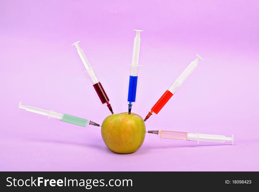 Five syringe with a color liquid, in an apple. Five syringe with a color liquid, in an apple