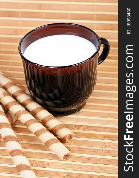 Cup with milk and cookies on bamboo cover