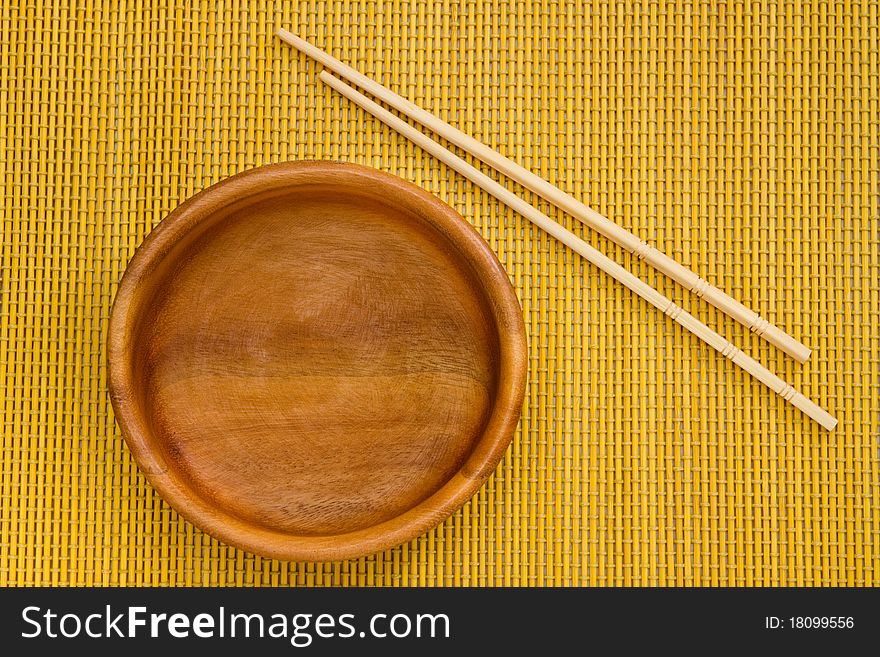 Empty Wooden Bowl with Chopsticks on bamboo mat