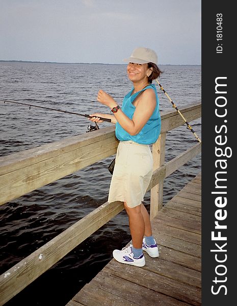 Photo of hispanic woman trying her luck on a Sanibel Island Florida fishing pier. Though no fish were caught that day, being in the outdoors was enjoyable.