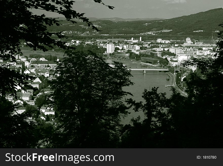 View from a hill (Freinberg) through trees on Linz coloured black and white. On the left side Urfahr (district of Linz) on the right Center of Linz. In the middle the river Danube and the Nibelungen-bridge connecting Urfahr with center-Linz. View from a hill (Freinberg) through trees on Linz coloured black and white. On the left side Urfahr (district of Linz) on the right Center of Linz. In the middle the river Danube and the Nibelungen-bridge connecting Urfahr with center-Linz.