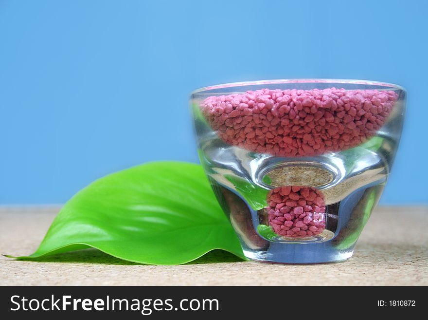 A green leaf with pink stones in a glass - wellness - spa. A green leaf with pink stones in a glass - wellness - spa