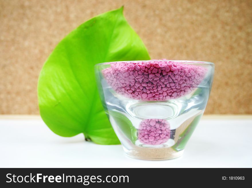 A green leaf with pink stones in a glass - wellness - spa. A green leaf with pink stones in a glass - wellness - spa