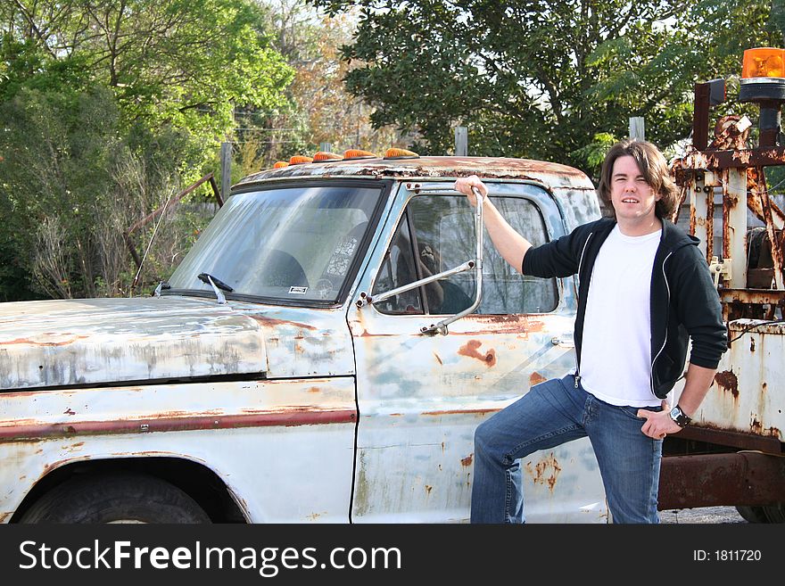 Photo of a young man standing outside by an old abandon truck. Photo of a young man standing outside by an old abandon truck