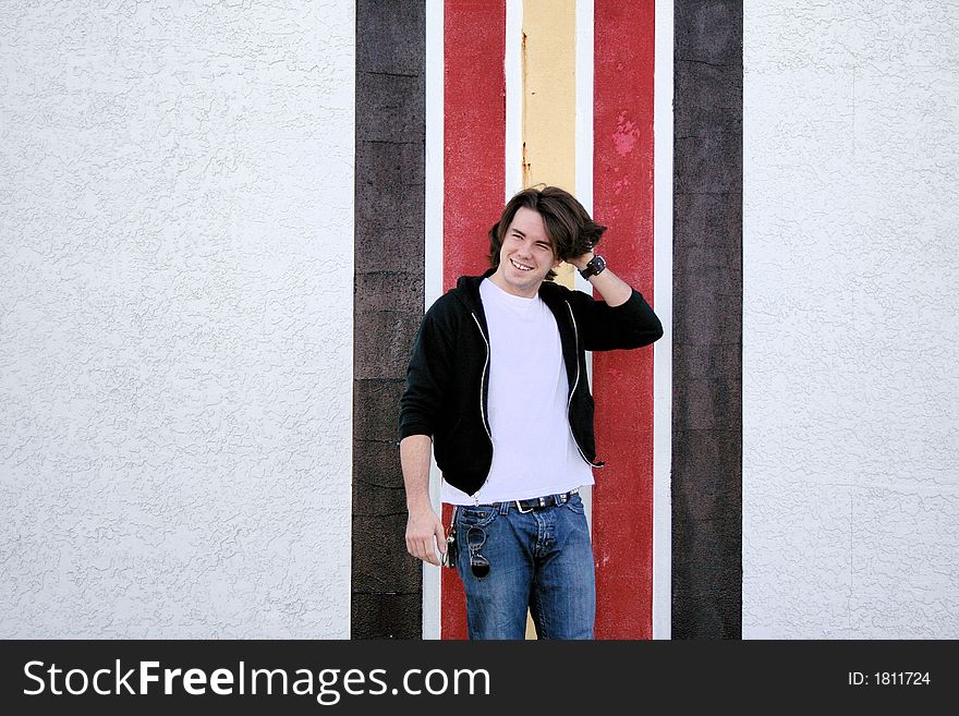 Photo of a young man standing outside in front of a striped wall. Photo of a young man standing outside in front of a striped wall