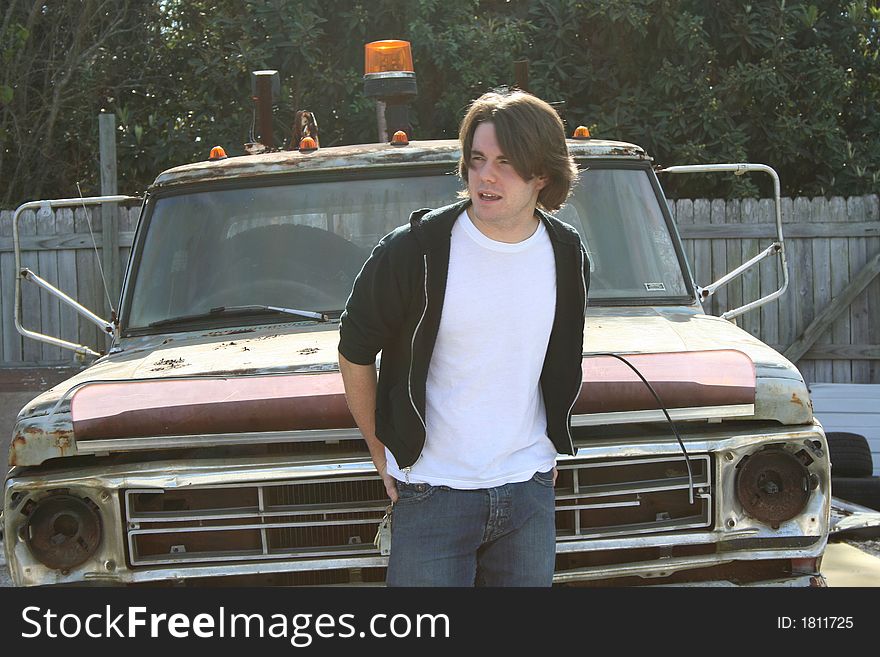 Photo of a young man standing outside by an old abandon truck. Photo of a young man standing outside by an old abandon truck