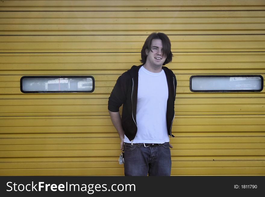 Photo of a young man standing against the overhead doors of an building. Photo of a young man standing against the overhead doors of an building
