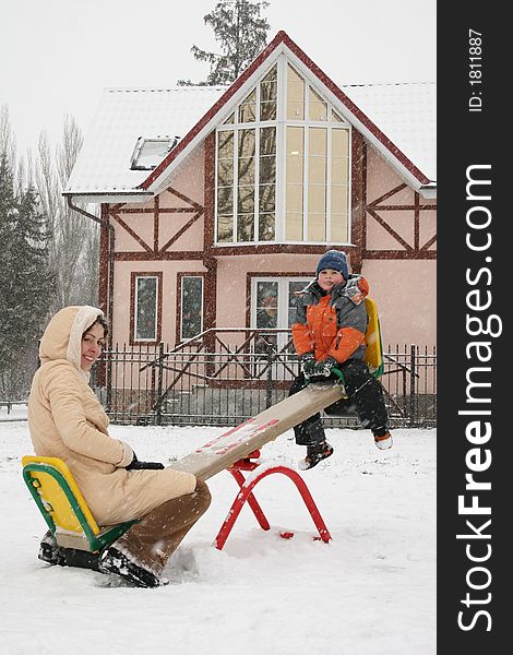 Mother with son on winter seesaw