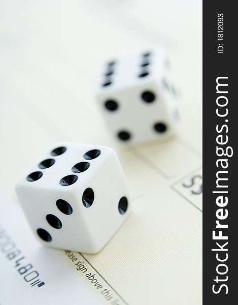 Two dice on a check show double six (shallow depth of field used)