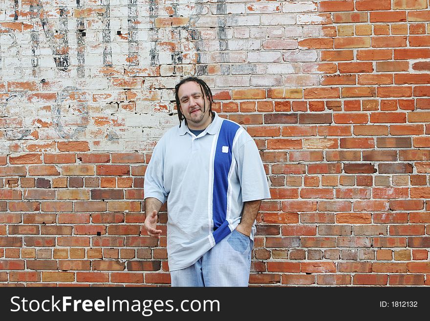 Photo of a young man leaning against a brickwall outside in an downtown area. Photo of a young man leaning against a brickwall outside in an downtown area.