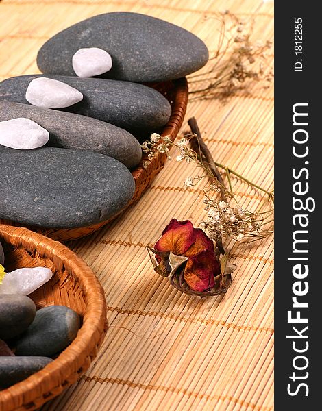 Natural pebbles and dried rose petals on the rattan background. Suitable for spa and relaxation setting. Natural pebbles and dried rose petals on the rattan background. Suitable for spa and relaxation setting.