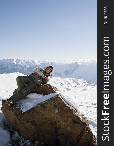 Snowboarder in relax, laying on big rock