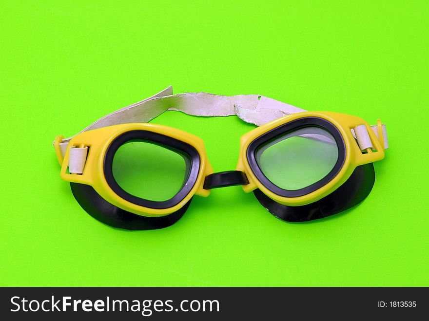 Yellow swimming glasses on green background. Yellow swimming glasses on green background