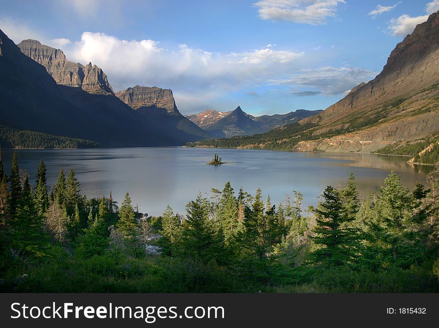 Small island in the center of a lake in Glacier National Park with surrounding mountains. Small island in the center of a lake in Glacier National Park with surrounding mountains
