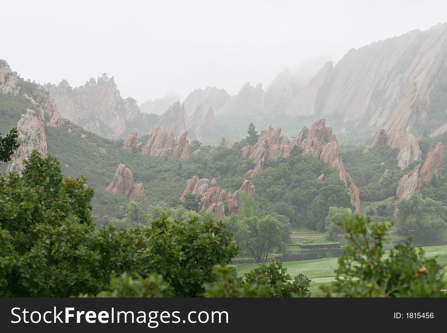 Jagged red rock outcroppings of Roxborough State Parkdisappearing into the fog with abundant green scrub oak. Jagged red rock outcroppings of Roxborough State Parkdisappearing into the fog with abundant green scrub oak