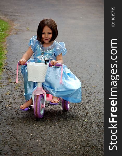 Four year old girl dressed up in a princess gown while riding a pink tricycle. Four year old girl dressed up in a princess gown while riding a pink tricycle.