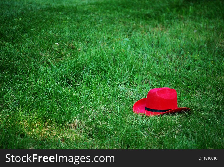 Red cowboy hat laying in the grass.