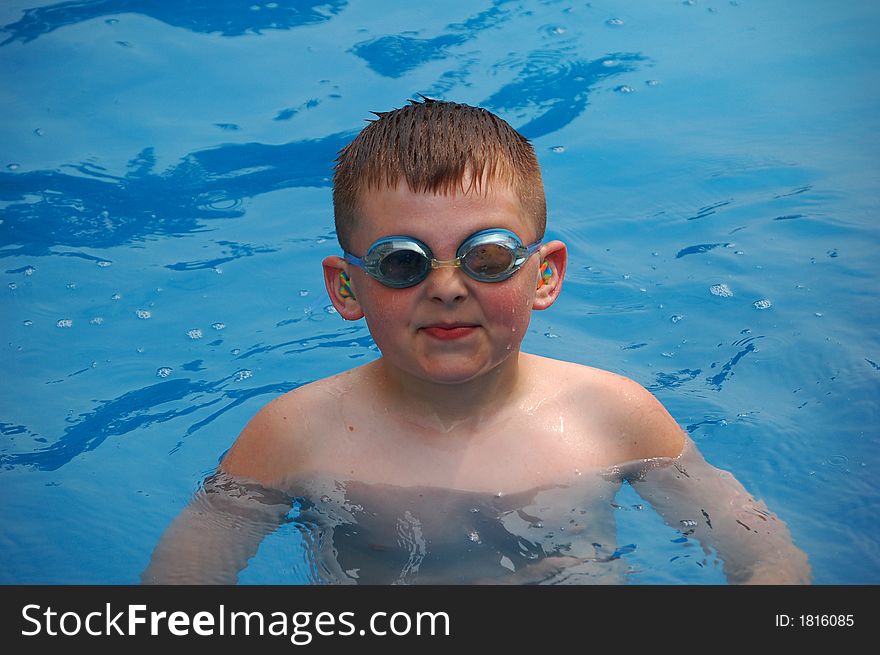 Young boy swimming with goggles and ear plugs. Young boy swimming with goggles and ear plugs.