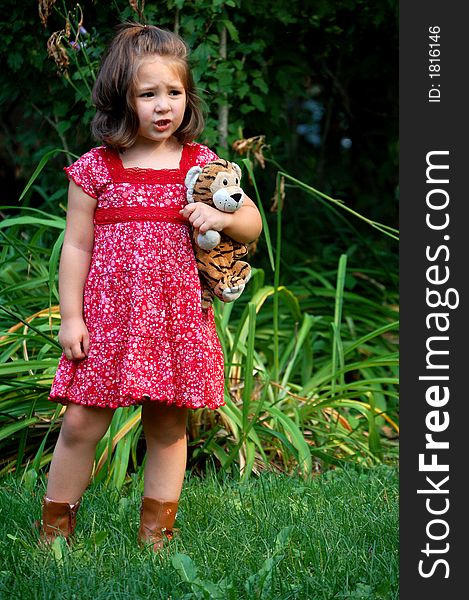 Four year old girl standing with her stuffed animal tiger. She has a worried look. Four year old girl standing with her stuffed animal tiger. She has a worried look.