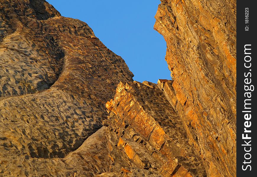 Orange seaside rocks against blue sky