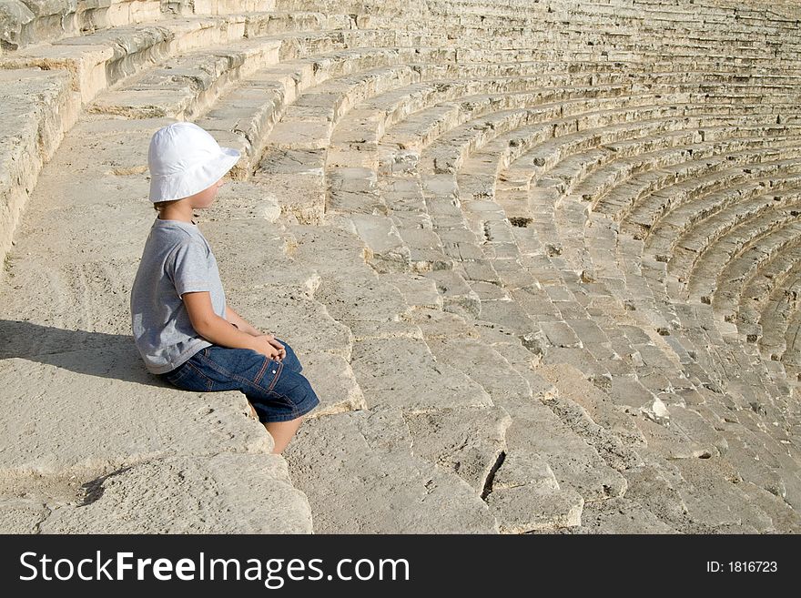 A small boy sitting in an amphitheatre