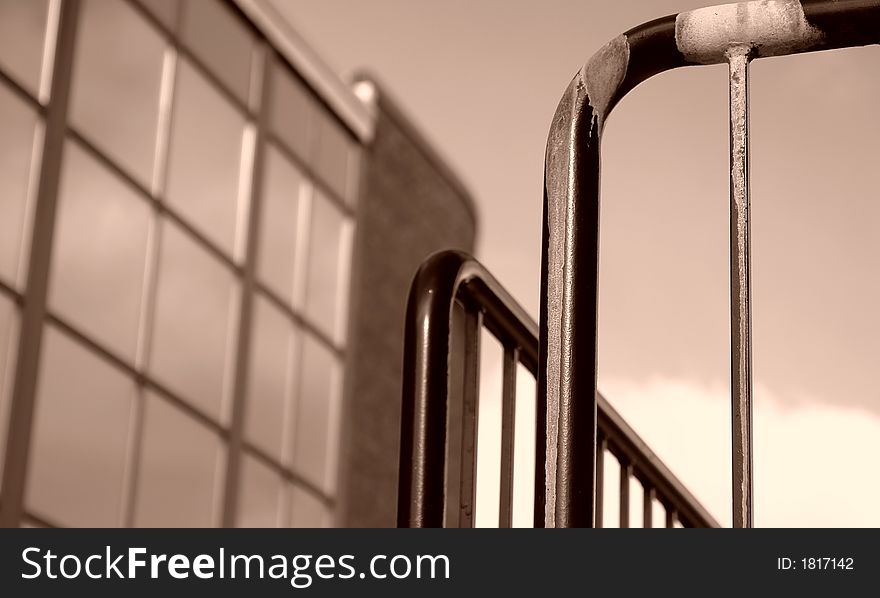 Sepia toned image of iron railing with building in background. Sepia toned image of iron railing with building in background