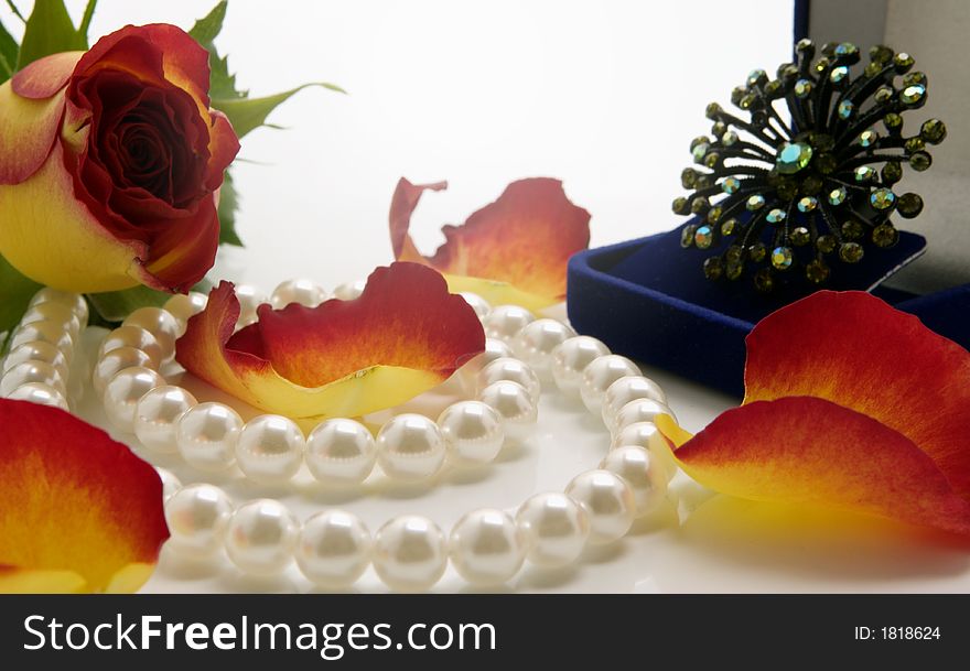 White pearl necklace and petals of roses over white background. White pearl necklace and petals of roses over white background