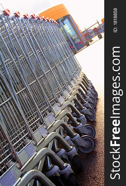 Shopping carts in a row towards entrance of a shopping mall.