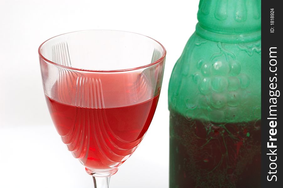 Red glass of wine and a green bottle