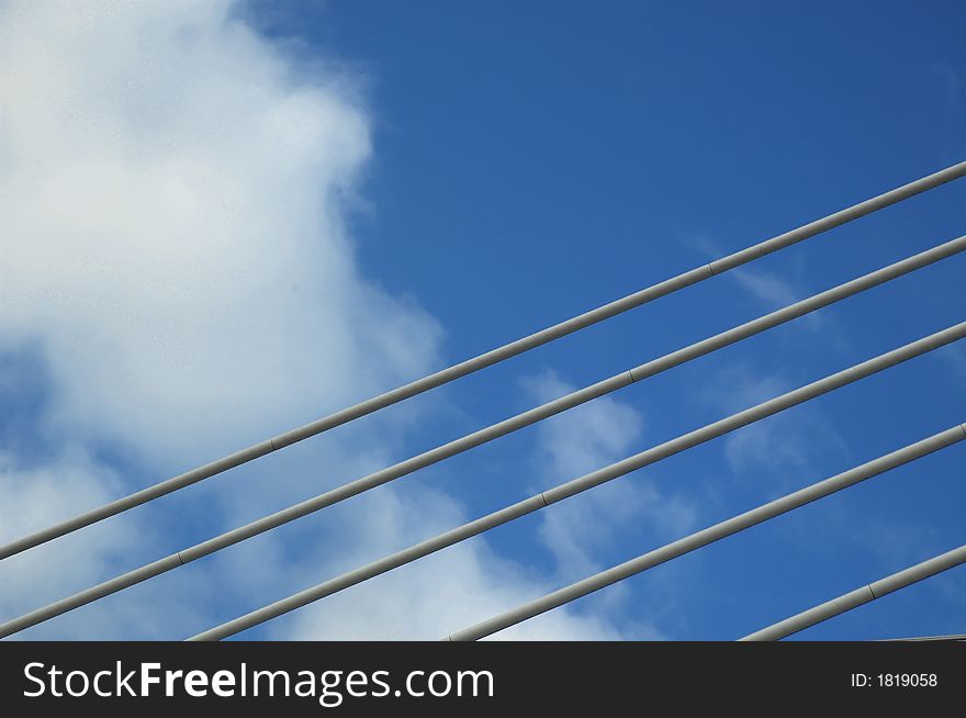 Modern bridge detail and blue sky with puffy clouds.