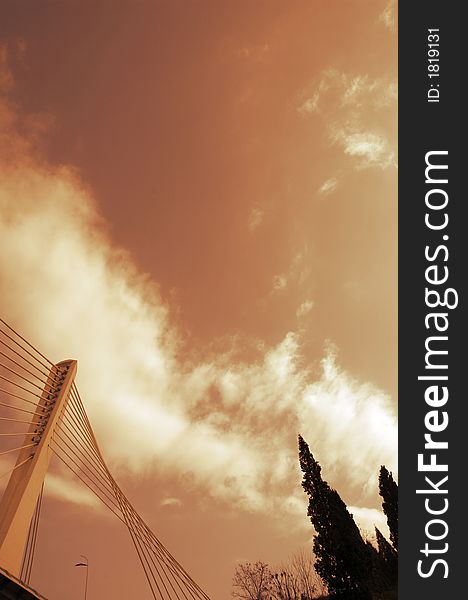 Detail of modern bridge with sky and clouds in background. Trees on the right side. Sepia toning. Detail of modern bridge with sky and clouds in background. Trees on the right side. Sepia toning.