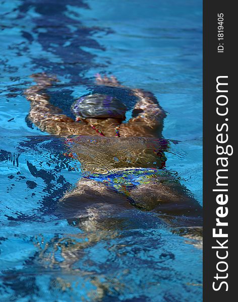 Young woman's back swimming underwater. Young woman's back swimming underwater.