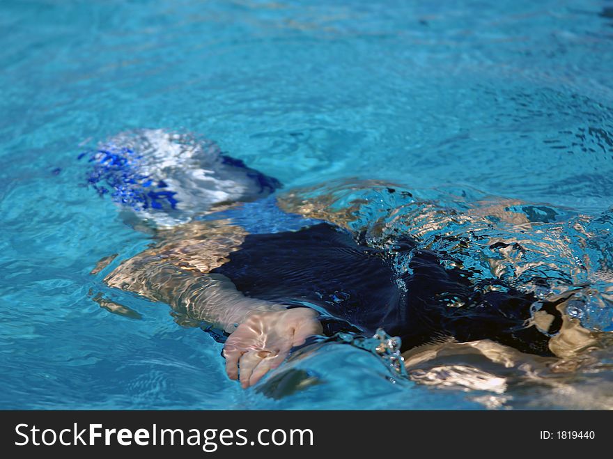 Little girl swimming under water after flip turn at swim meet. Little girl swimming under water after flip turn at swim meet.