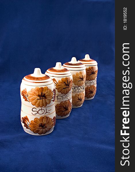 A four, ceramic containers for spices isolated on dark blue background.