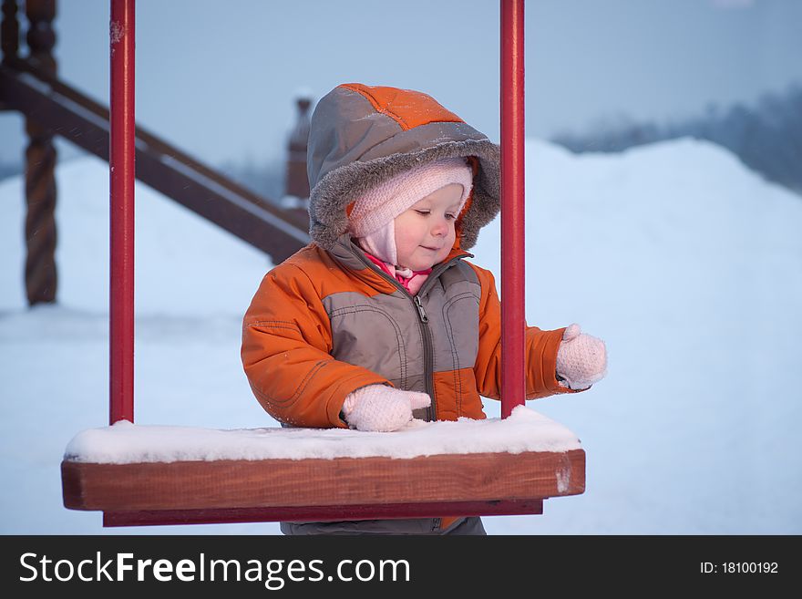 Cute baby stay and hold kids swing in winter evening. Cute baby stay and hold kids swing in winter evening