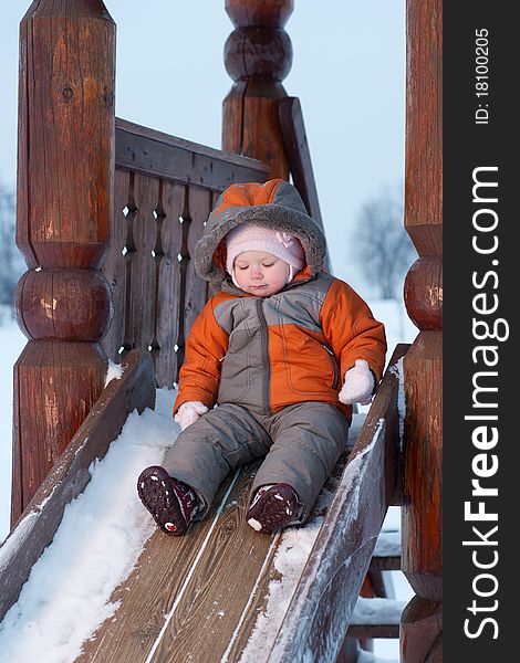 Cute baby prepare to slide down the slides for children in winter