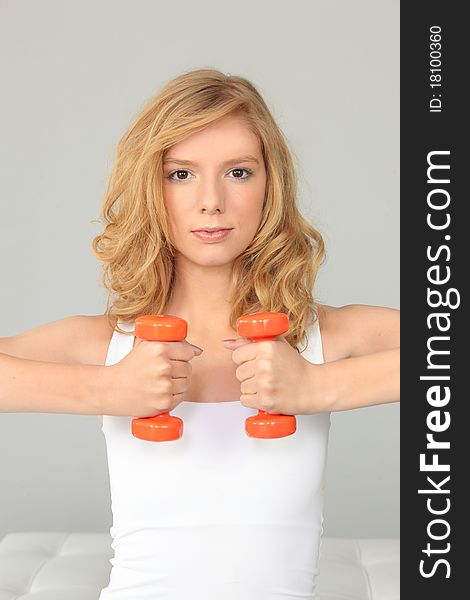 Young fair-haired woman holding dumbbells. Young fair-haired woman holding dumbbells